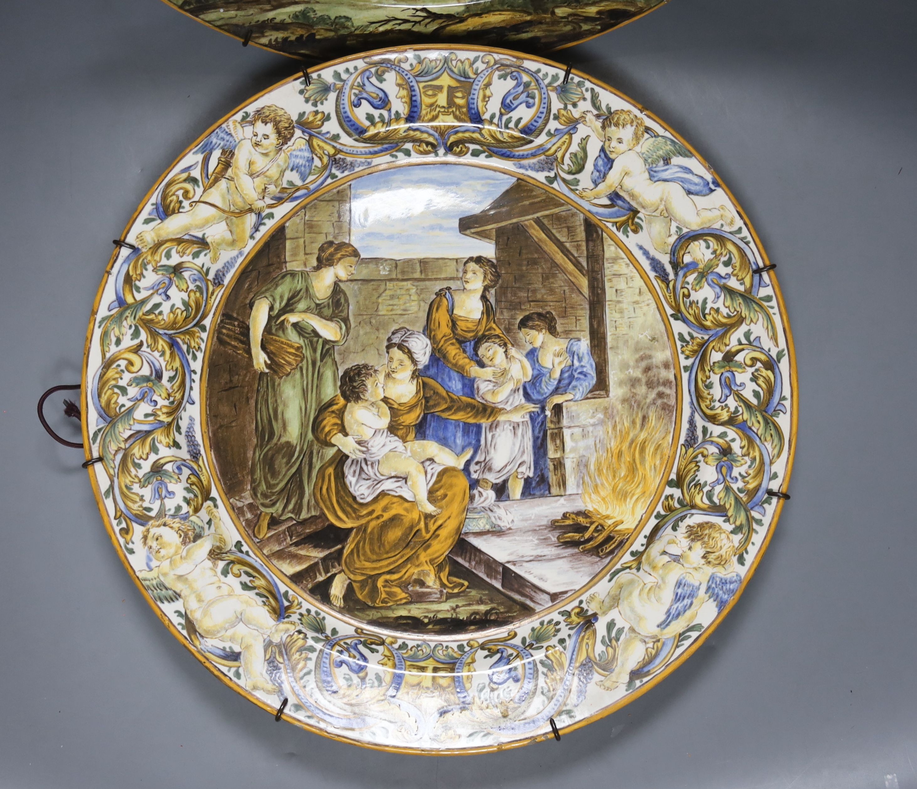 Two Italian Urbano style chargers ‘The Finding of Moses’ and figures by a fire, 37 cms diameter.
